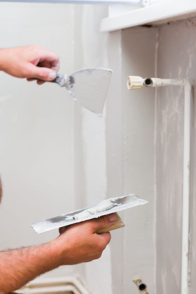 Un hombre está enyesando una pared con una espátula.