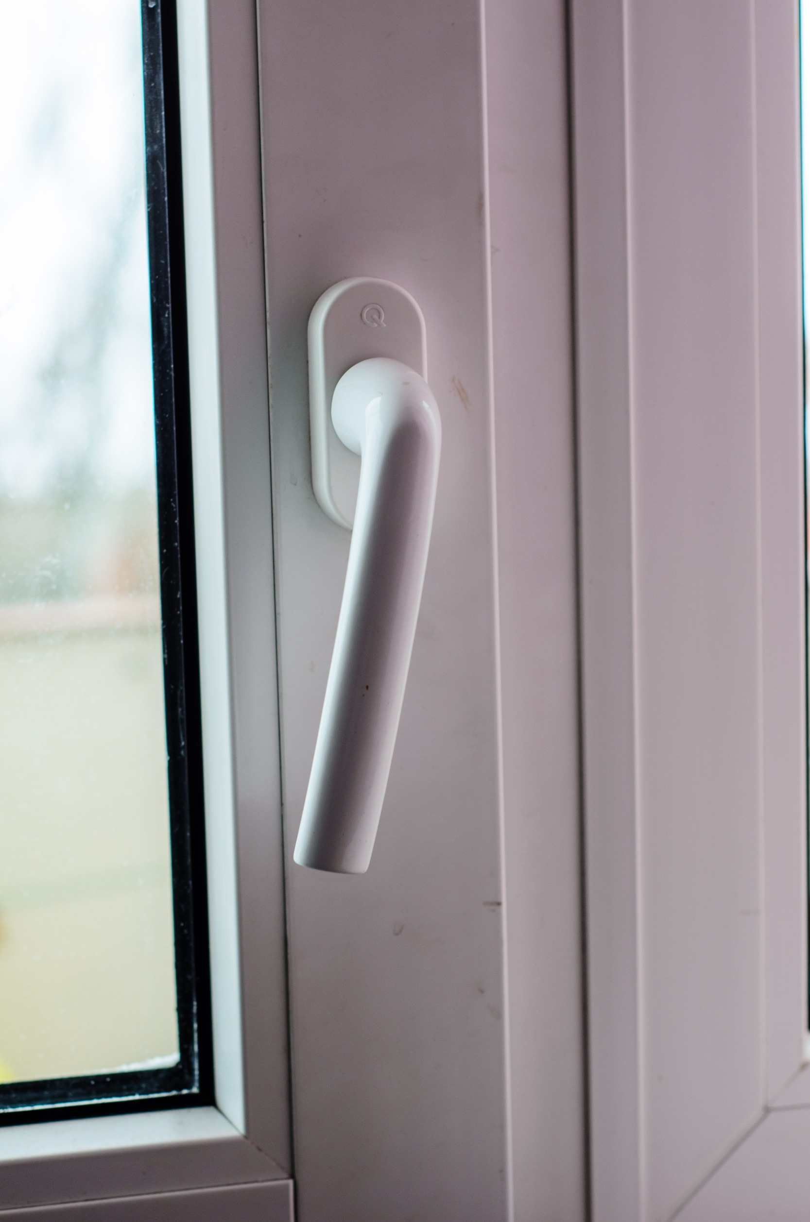 Un primer plano de una manija de ventana blanca en una ventana blanca.