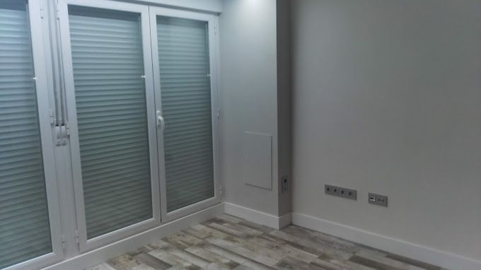 Una habitación con muchas ventanas y suelo de madera.