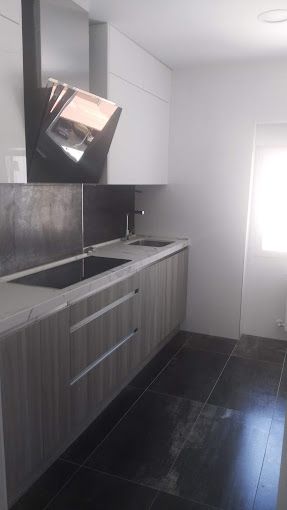 Una cocina con gabinetes blancos, un horno, un fregadero y una ventana.