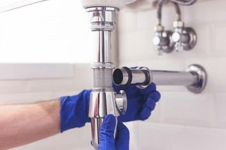 Un fontanero está arreglando una tubería del lavabo de un baño.