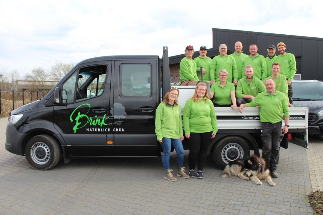 Eine Gruppe von Menschen in grünen Hemden posiert vor einem Lastwagen für ein Foto.