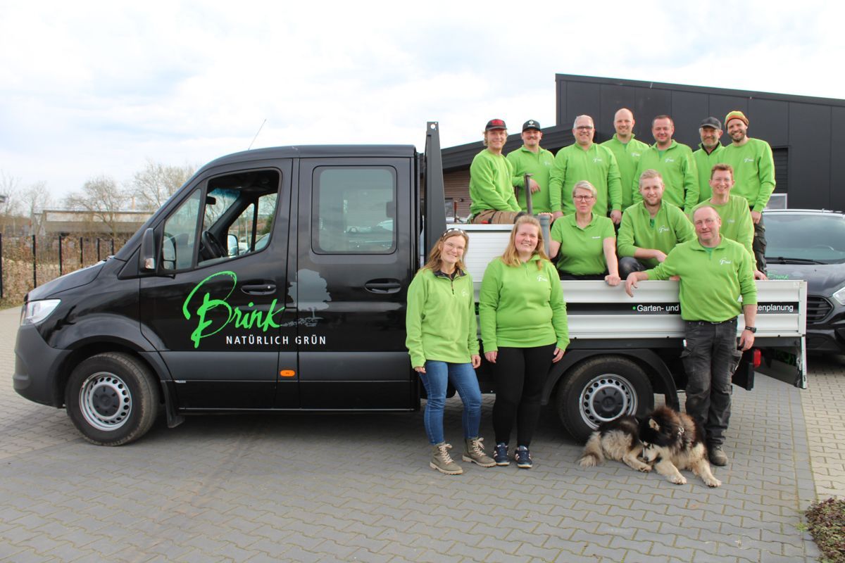 Eine Gruppe von Menschen in grünen Hemden posiert vor einem Lastwagen für ein Foto.