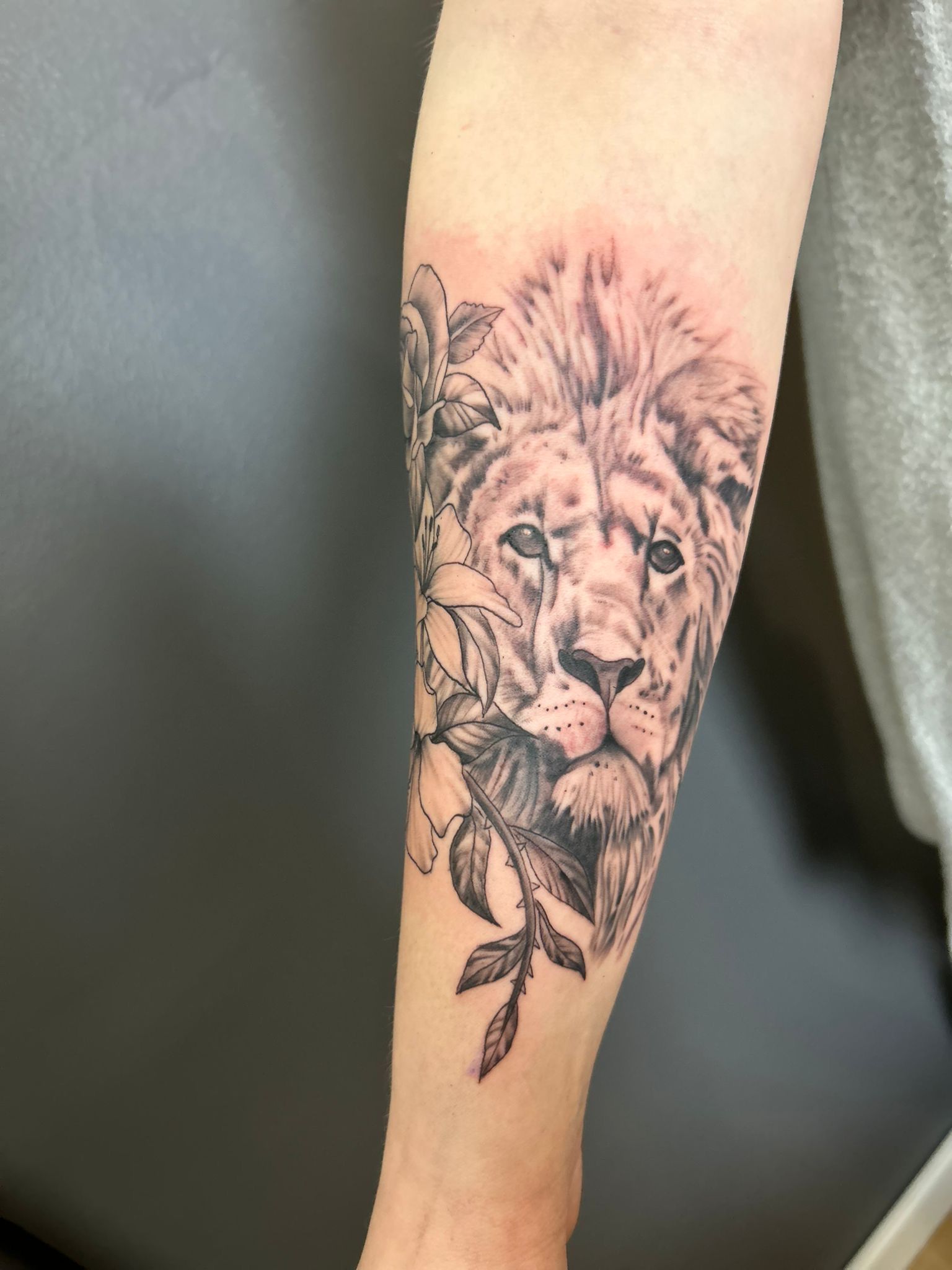 Eine Person hat ein Löwentattoo auf dem Unterarm
