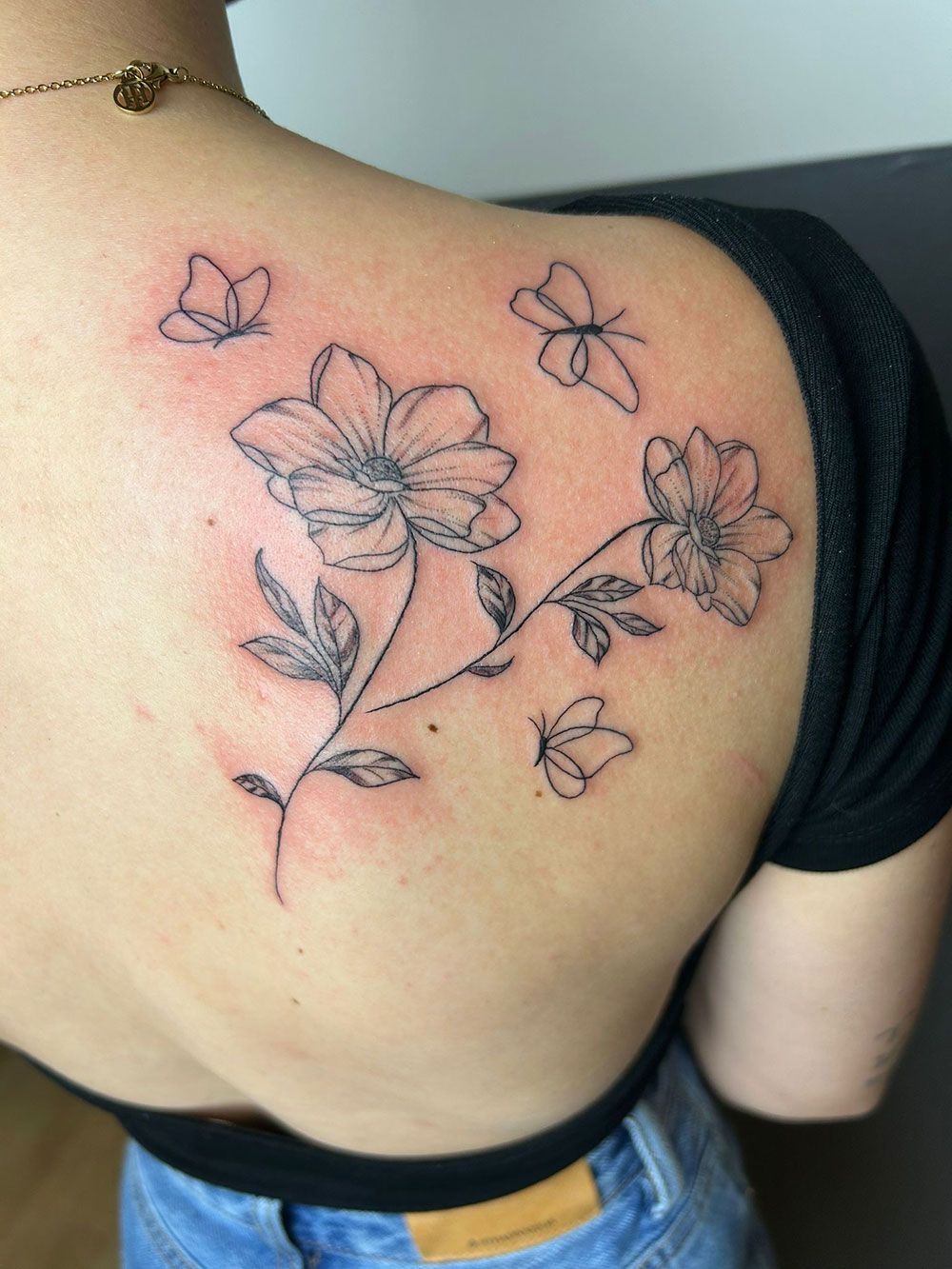 Eine Frau hat eine Tätowierung mit Blumen und Schmetterlingen auf ihrem Rücken