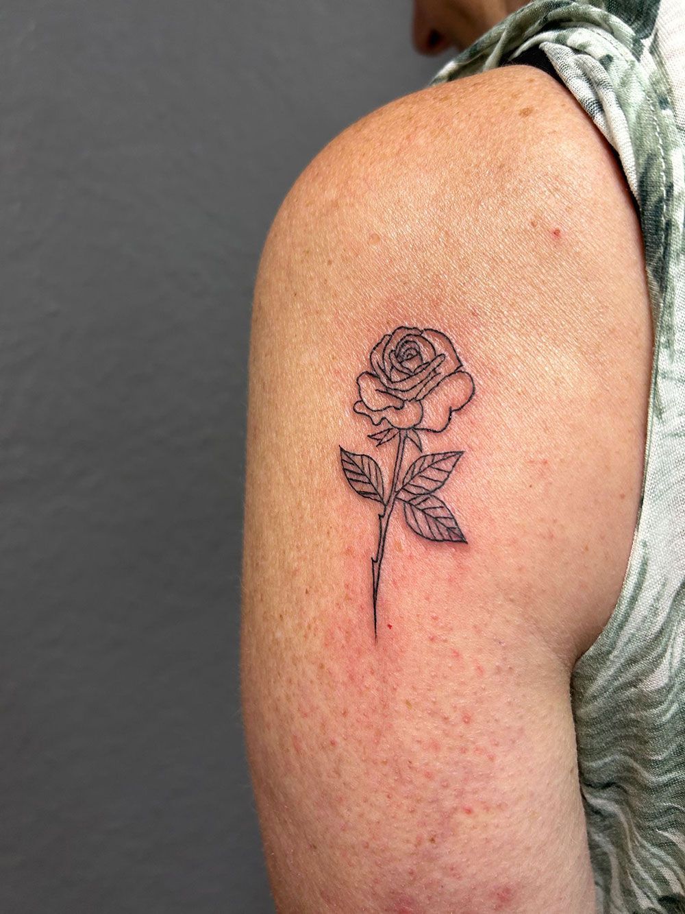 Eine Frau hat eine kleine Tätowierung einer Rose auf ihrer Schulter.