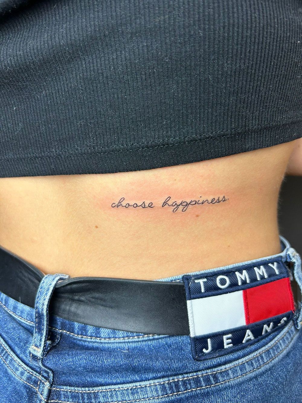 Eine Frau hat eine Tätowierung auf ihrem Rücken mit der Aufschrift „Some Happiness“ (etwas Glück).