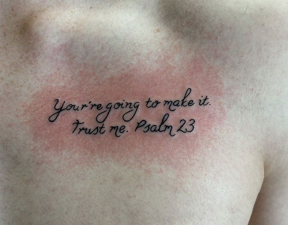 Eine Person hat ein Tattoo auf der Brust, auf dem steht: „Du wirst es schaffen, vertrau mir, Psalm 23“