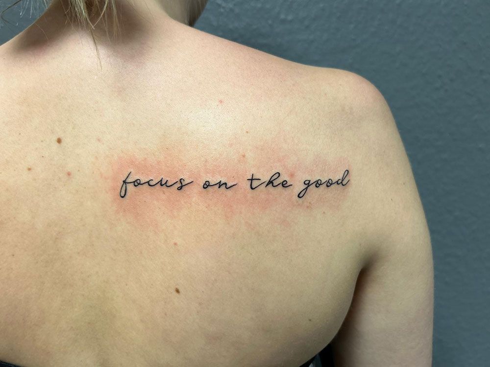 Eine Frau hat ein Tattoo auf dem Rücken mit der Aufschrift „Konzentriere dich auf das Gute“
