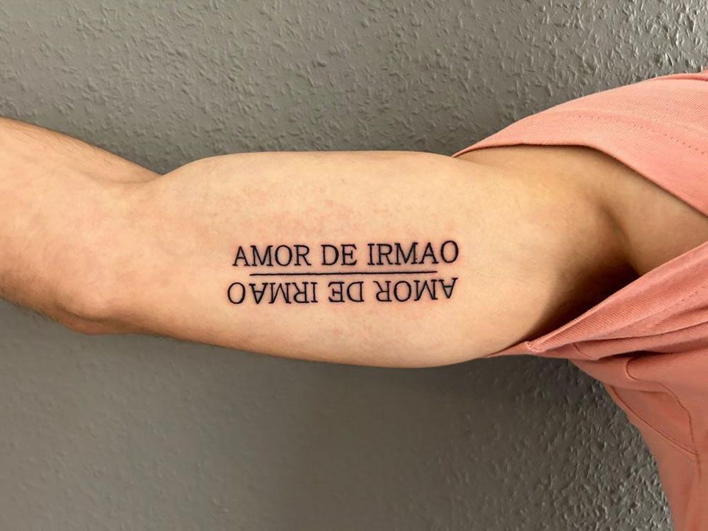 Eine Person hat ein Tattoo auf dem Arm mit der Aufschrift „Amor de Irmão“