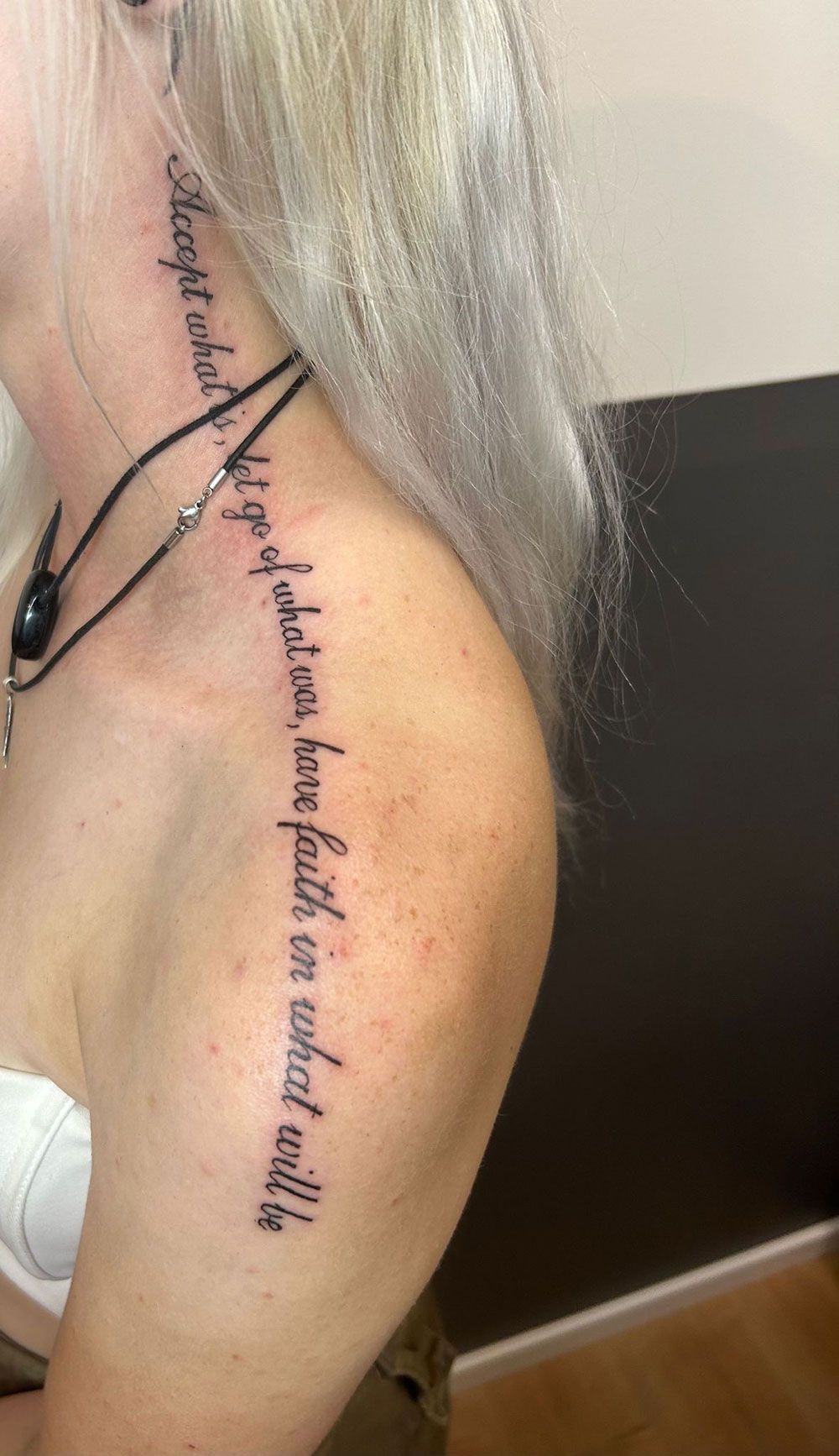 Eine Frau hat eine Tätowierung an Hals und Schulter.