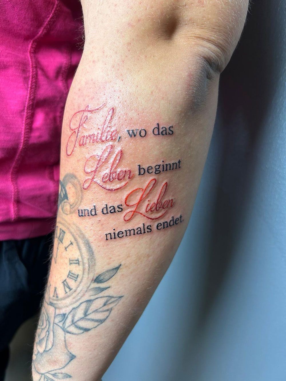 A person has a tattoo on their arm that says family wo das leben beginnt and das liebe niemals endet