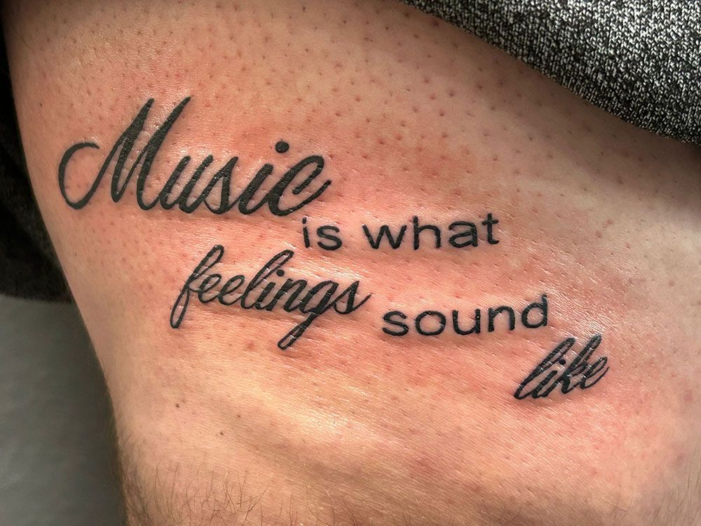 Eine Person hat eine Tätowierung an der Seite mit der Aufschrift „Musik ist das, wie Gefühle klingen“.