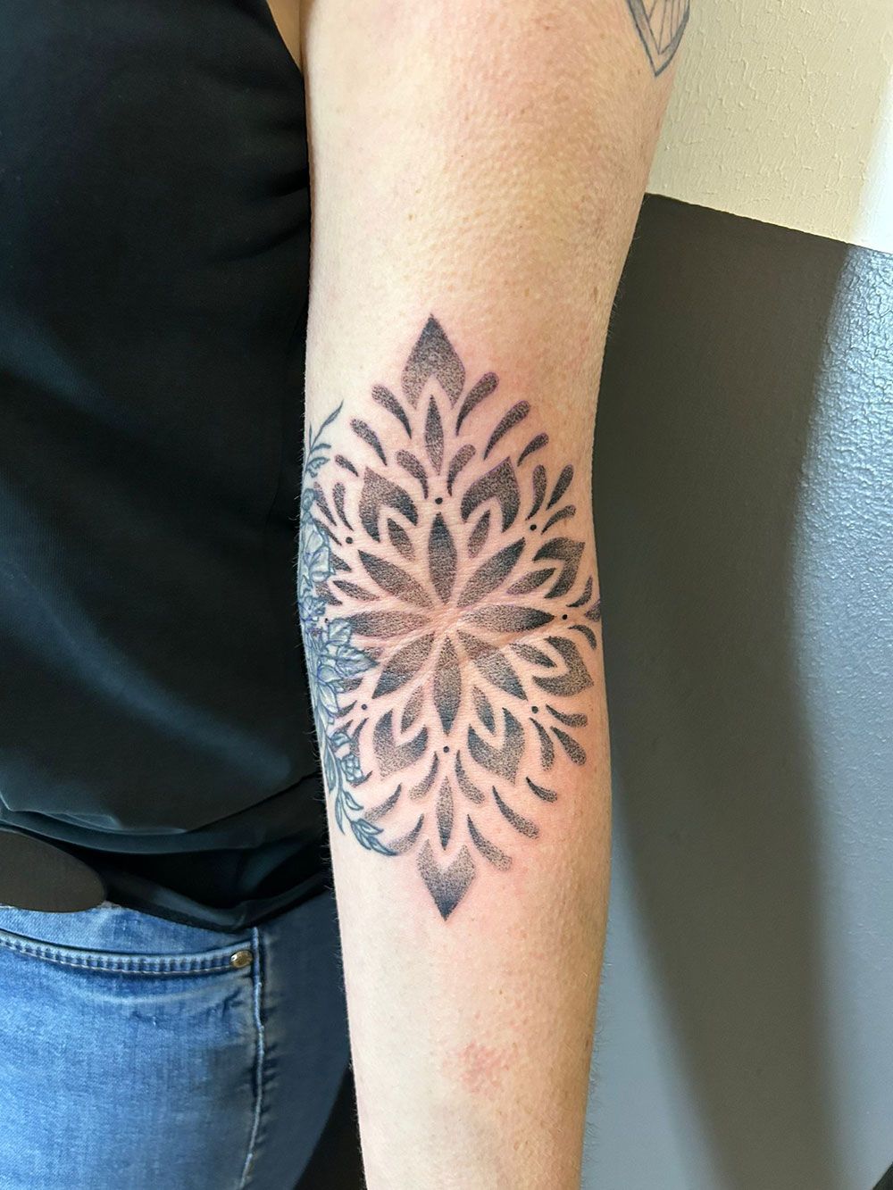 Eine Frau hat eine schwarz-weiße Tätowierung auf ihrem Ellbogen.