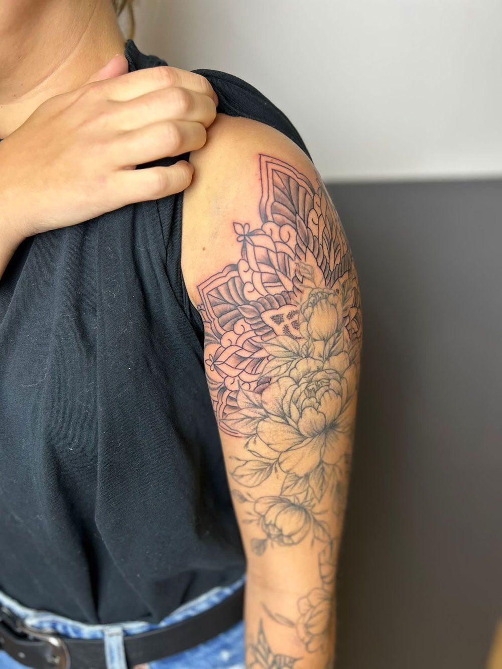 Eine Frau hat eine Tätowierung auf ihrem Arm, die wie ein Mandala aussieht.