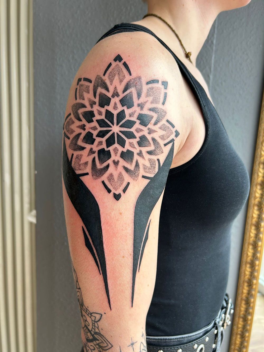 Eine Frau hat ein schwarz-weißes Tattoo auf ihrer Schulter