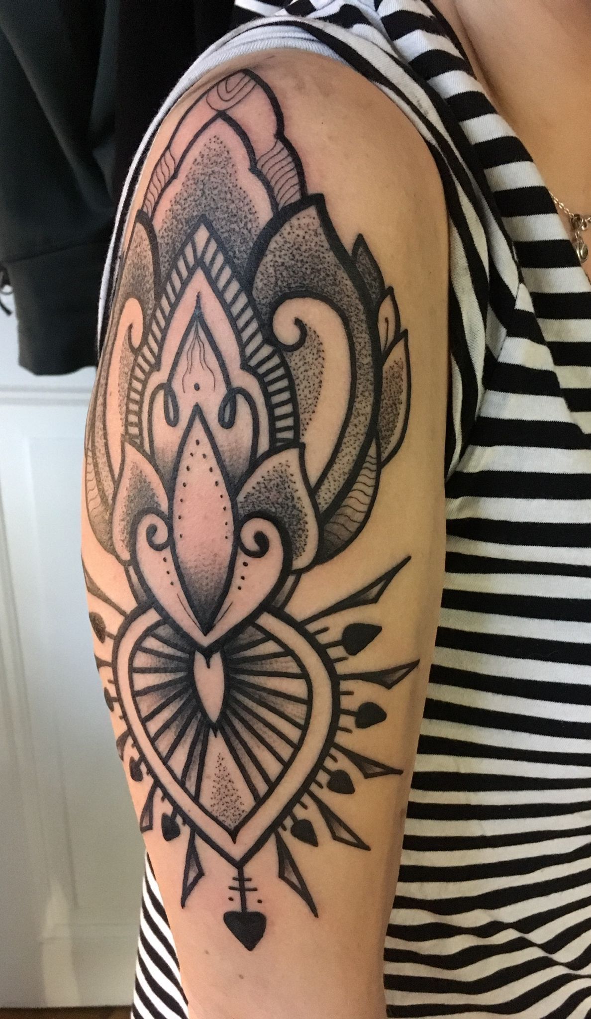 Eine Frau mit einem schwarz-weiß gestreiften Hemd hat eine Tätowierung auf ihrem Arm.