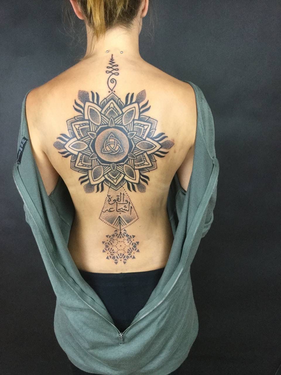 Eine Frau hat ein Mandala-Tattoo auf ihrem Rücken