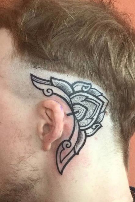 Ein Mann hat eine Tätowierung auf der Rückseite seines Ohrs.