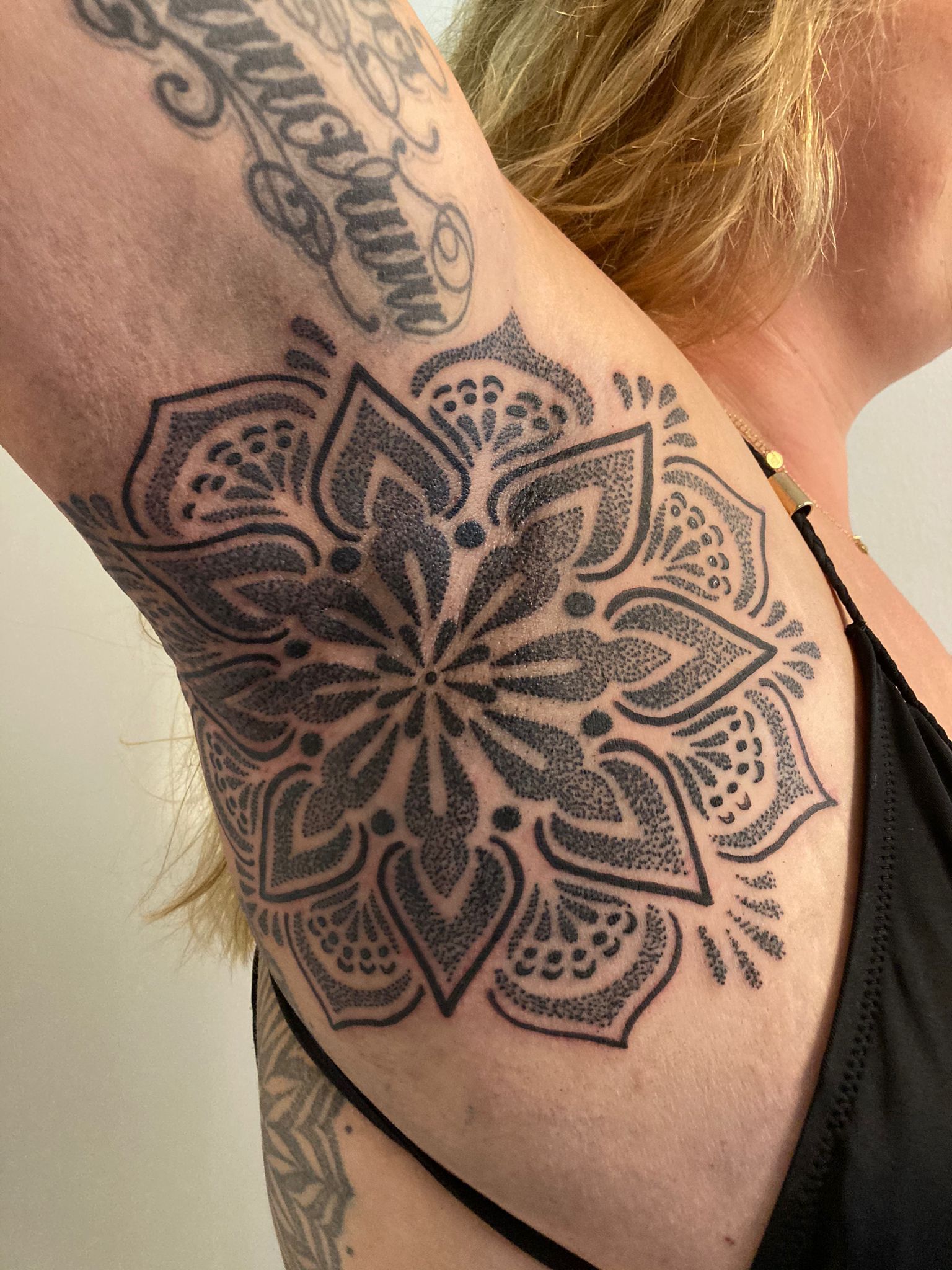 Eine Frau hat eine Blumentätowierung in ihrer Achselhöhle.