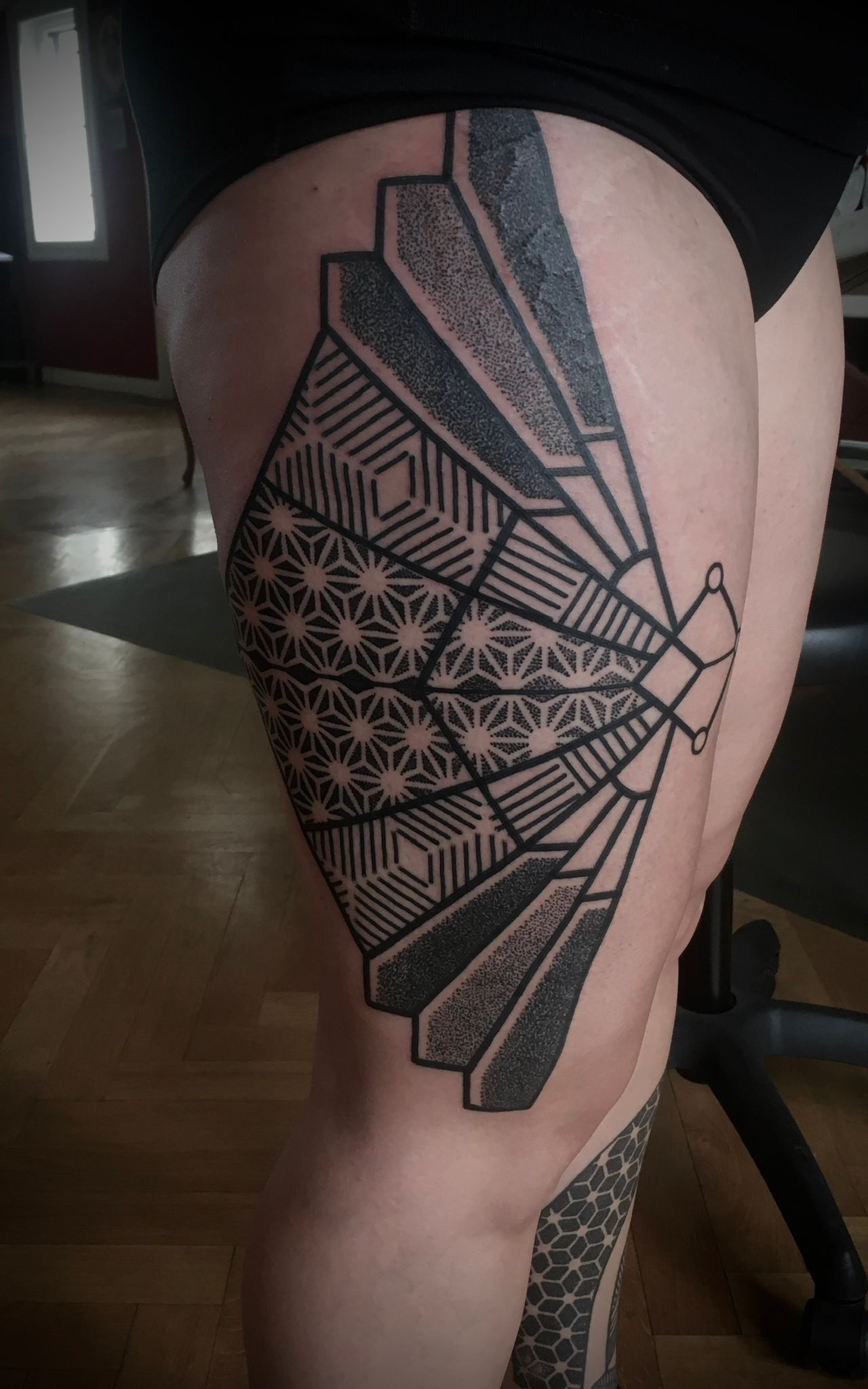 Eine Frau hat eine Tätowierung auf ihrem Bein, die wie ein Fächer aussieht.