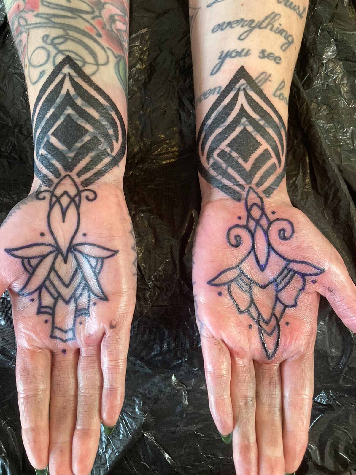 Eine Frau hat zwei Tattoos auf ihren Händen, darunter eine Lotusblume