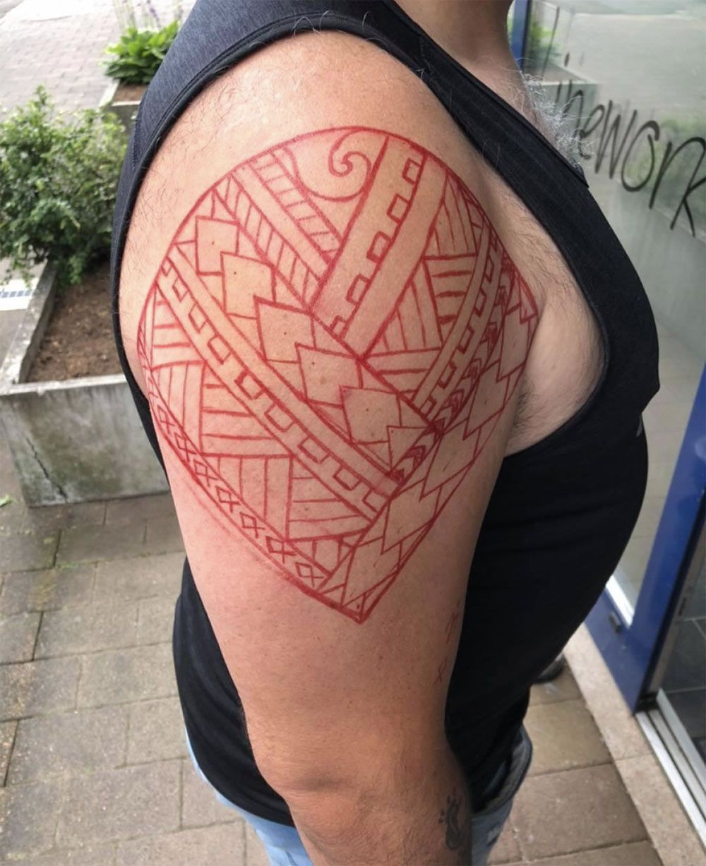 Ein Mann hat eine rote Tätowierung auf seinem Arm.