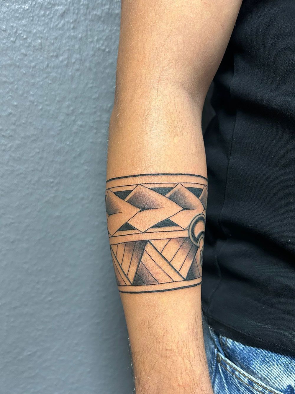 Ein Mann hat eine Tätowierung auf seinem Arm, die wie ein Armband aussieht.