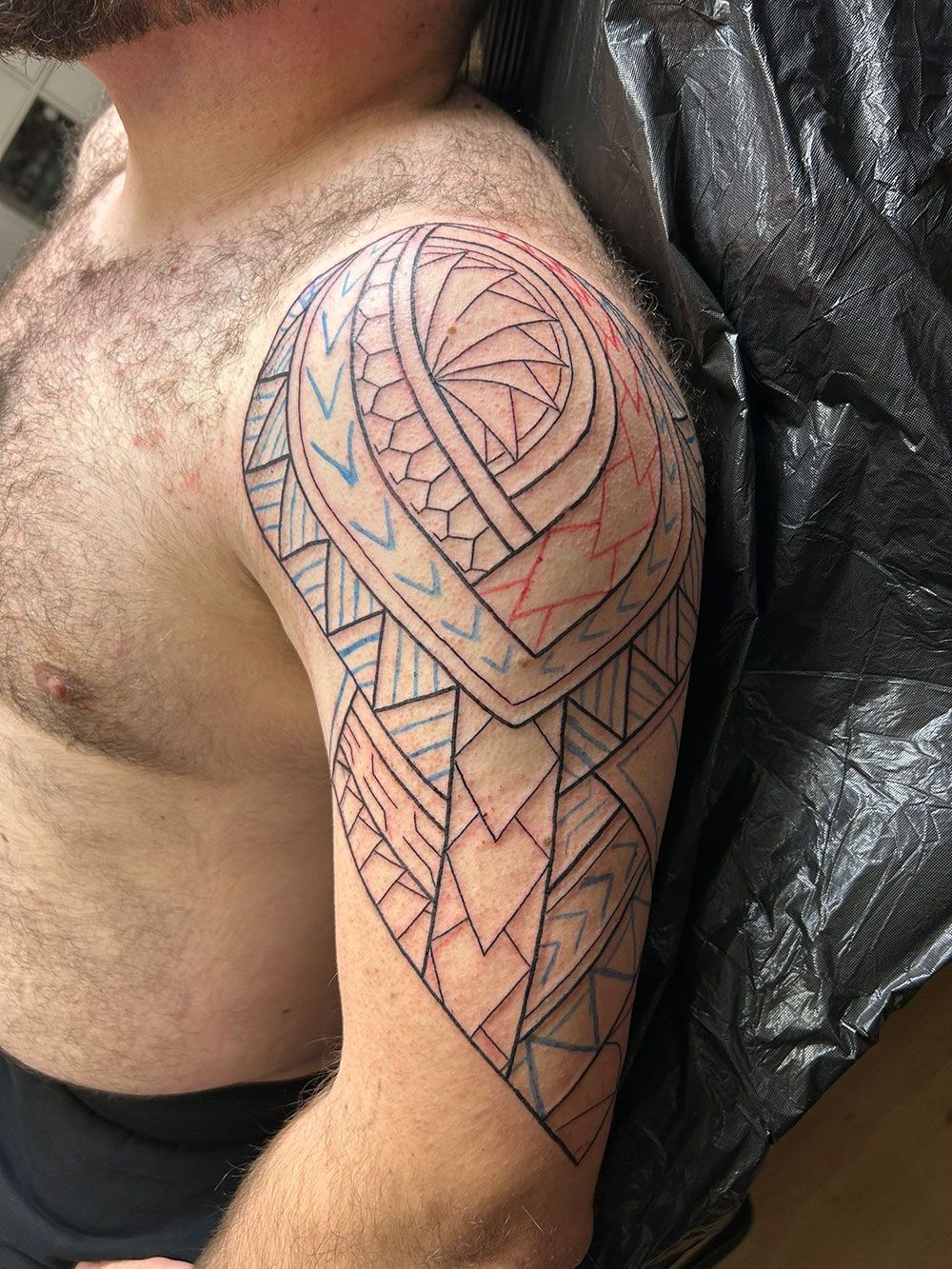 Ein Mann ohne Hemd hat eine Tätowierung auf seiner Schulter.