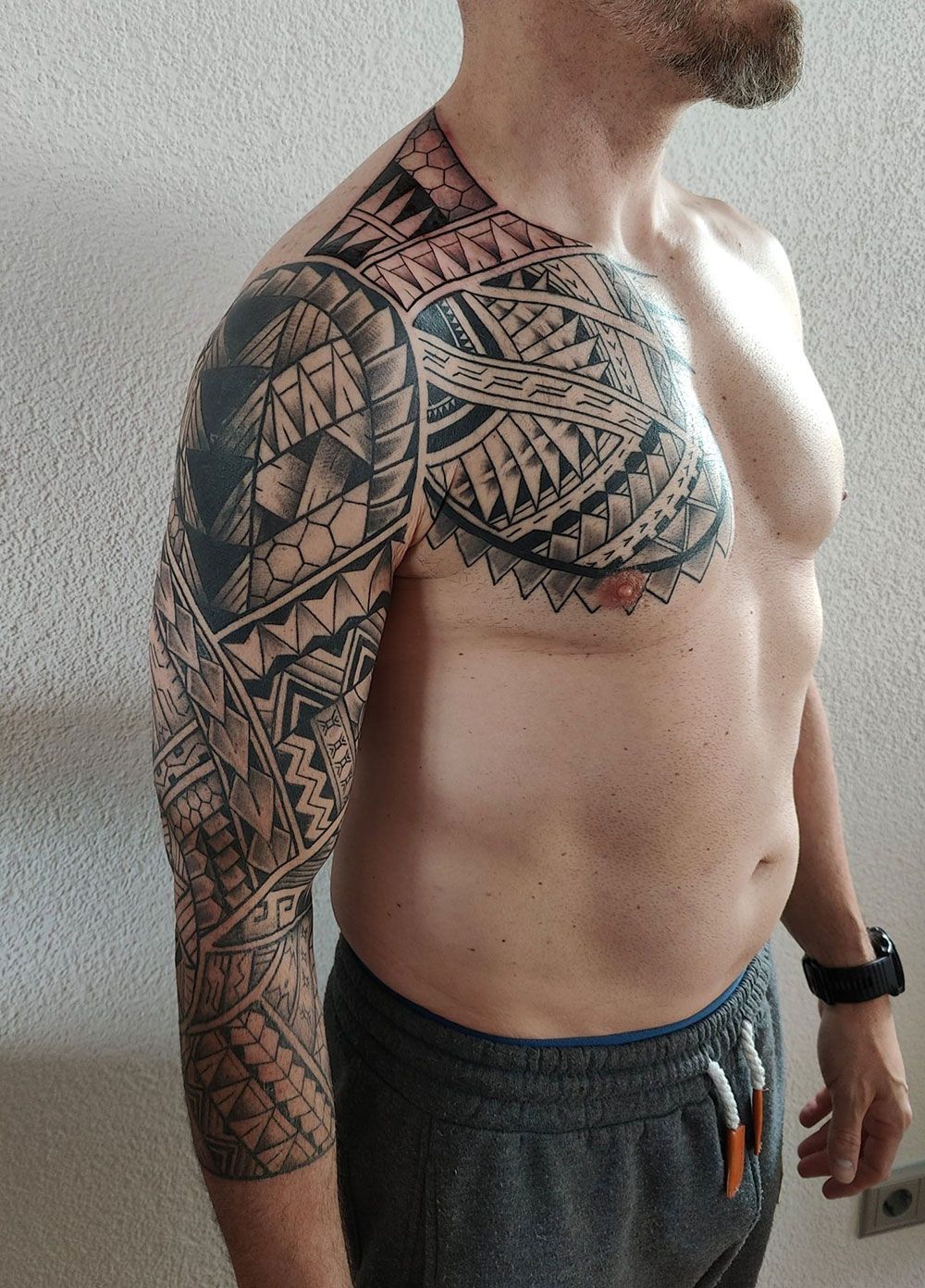 Ein Mann ohne Hemd mit einer Tätowierung auf der Brust und dem Arm