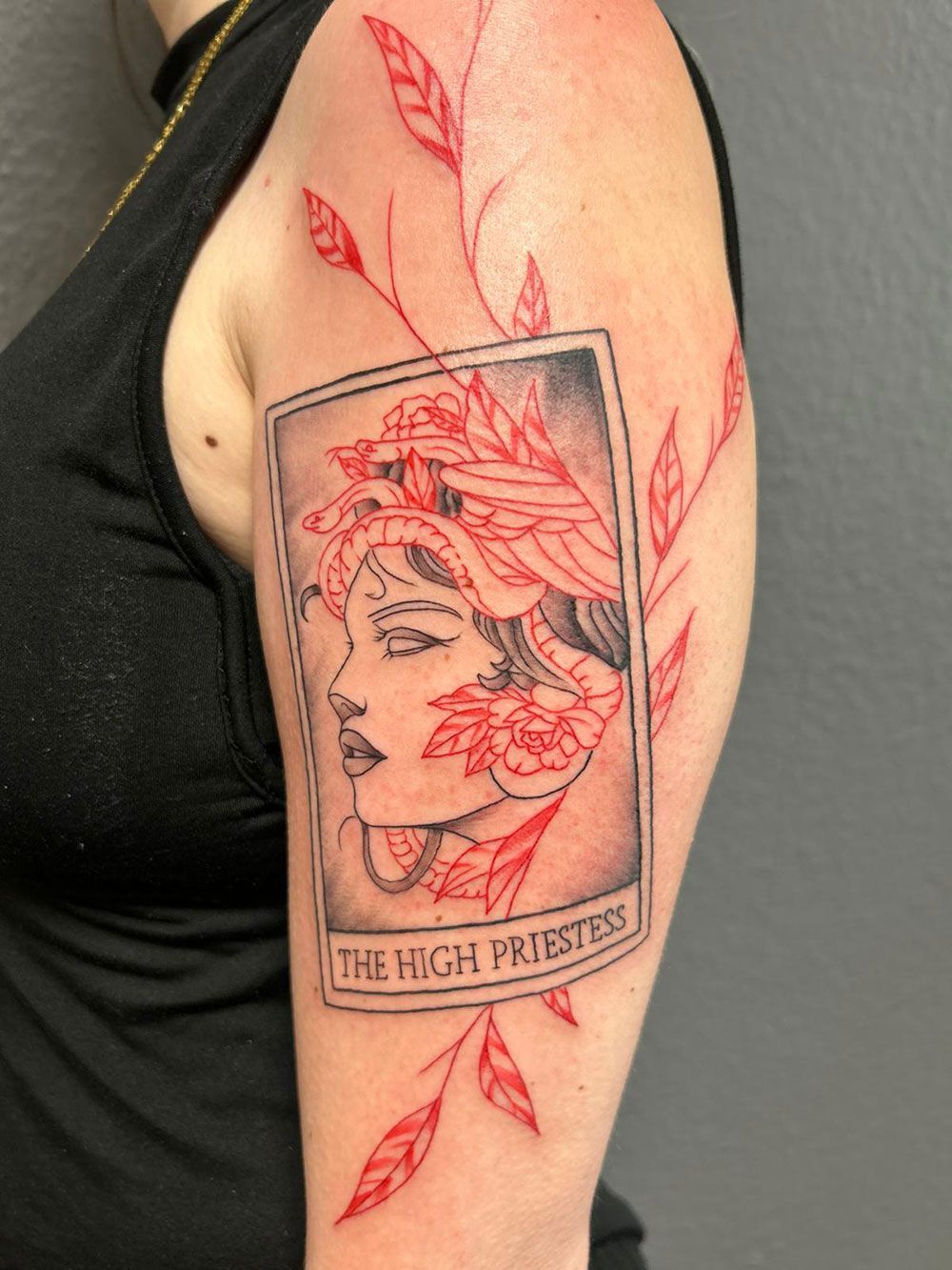 Eine Frau hat ein Tattoo auf ihrem Arm mit der Aufschrift „Hohepriesterin“