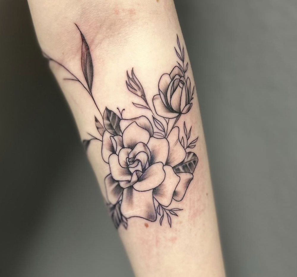 Ein schwarz-weißes Tattoo einer Rose auf dem Unterarm einer Person
