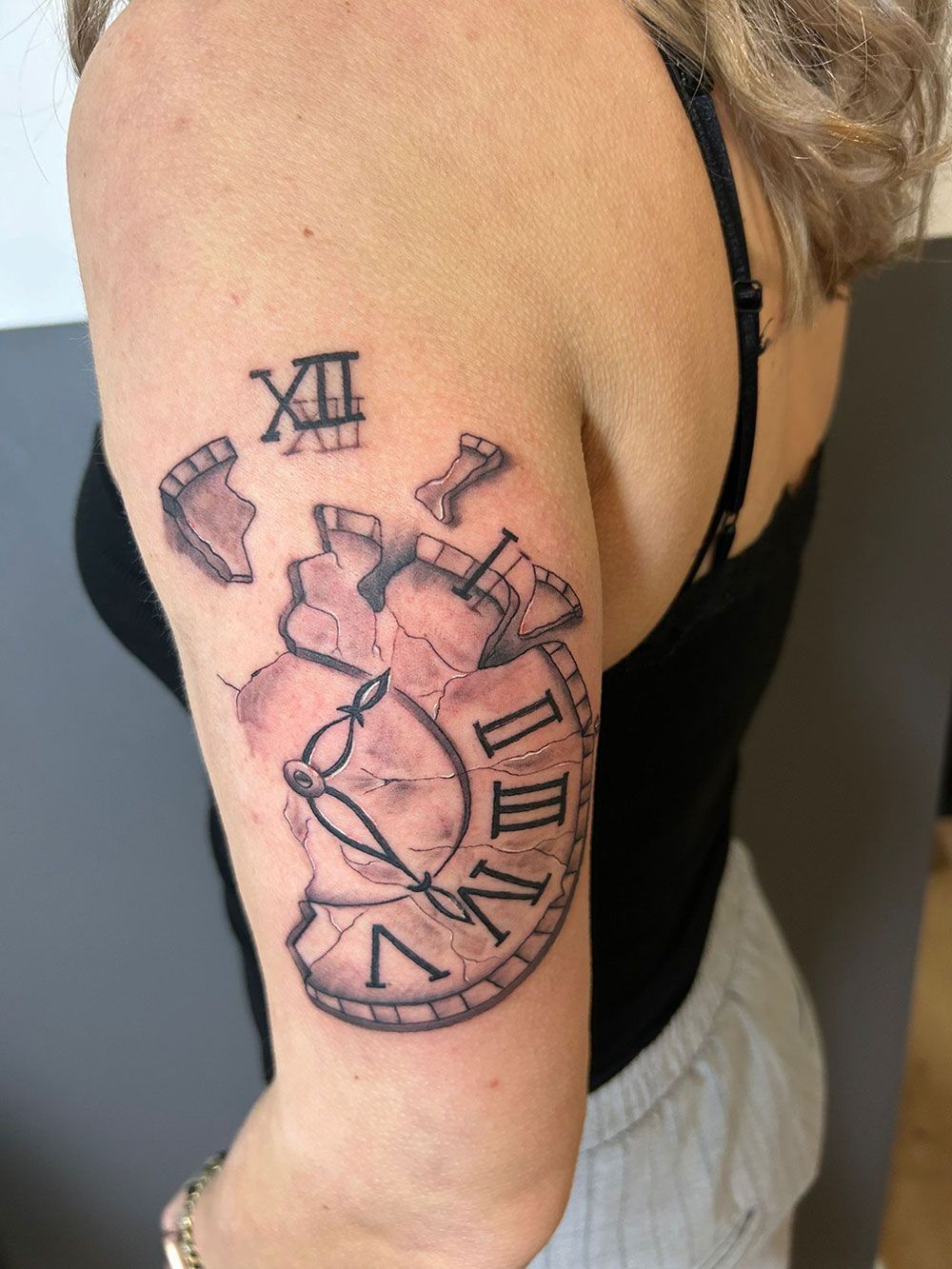 Eine Frau hat eine Tätowierung einer kaputten Uhr auf ihrem Arm