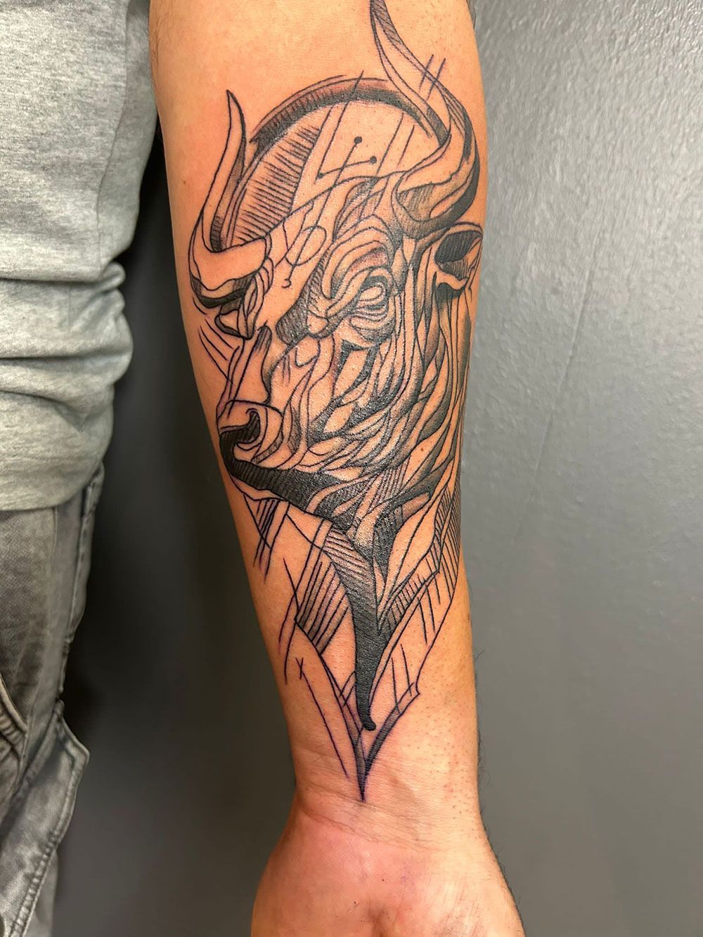 Ein Mann hat eine Stiertätowierung auf seinem Unterarm.