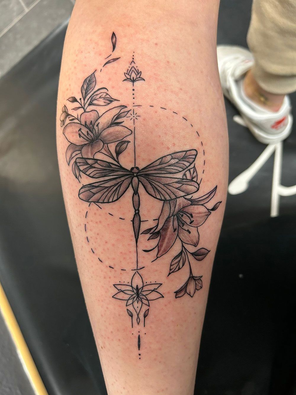 Eine Person hat eine Libellentätowierung auf ihrem Bein