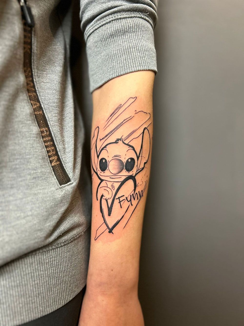 Eine Person hat eine Stichtätowierung auf dem Unterarm.