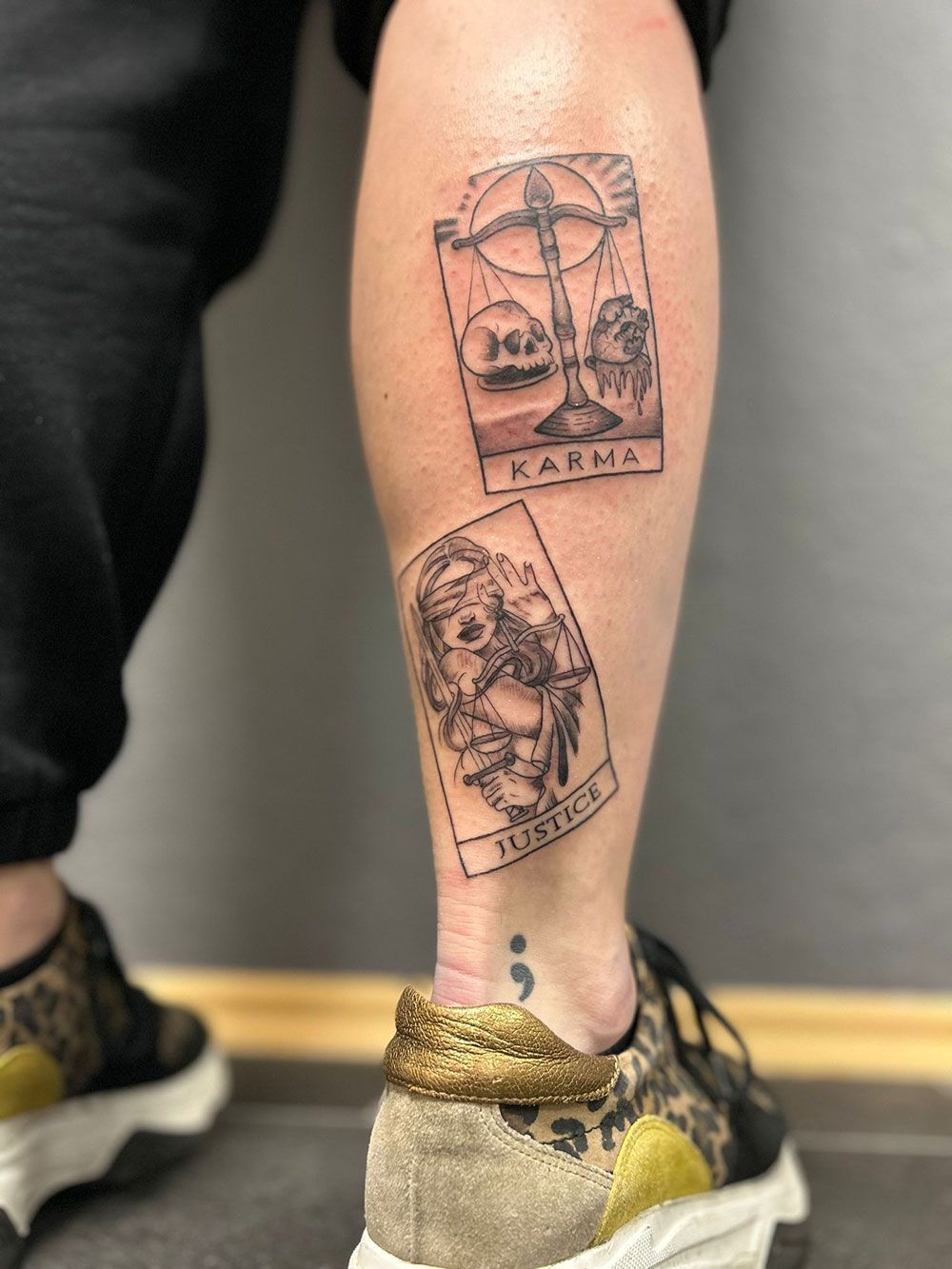 Eine Person mit einer Tätowierung auf dem Bein, die wie eine Tarotkarte aussieht.