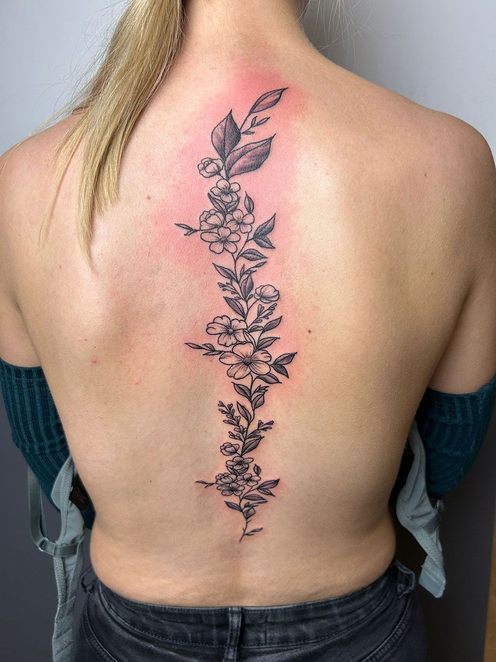 Eine Frau hat eine Blumentätowierung auf ihrem Rücken.