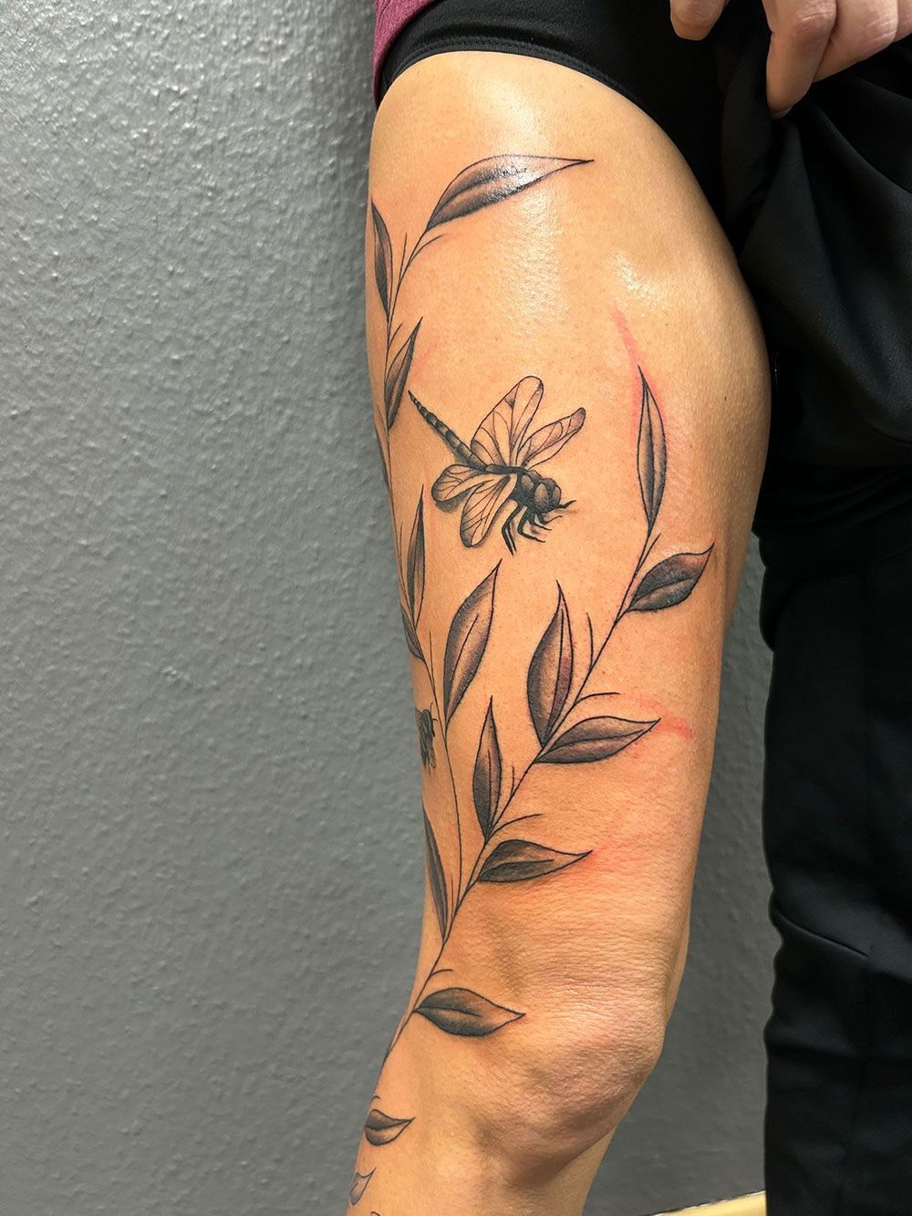 Eine Frau hat eine Libellentätowierung auf ihrem Bein.