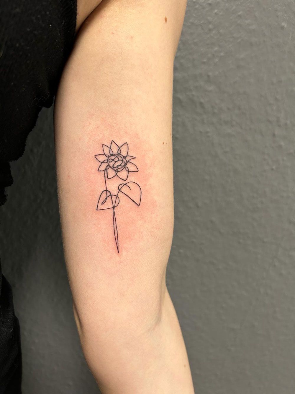 Eine Frau hat eine kleine Tätowierung einer Blume auf ihrem Arm
