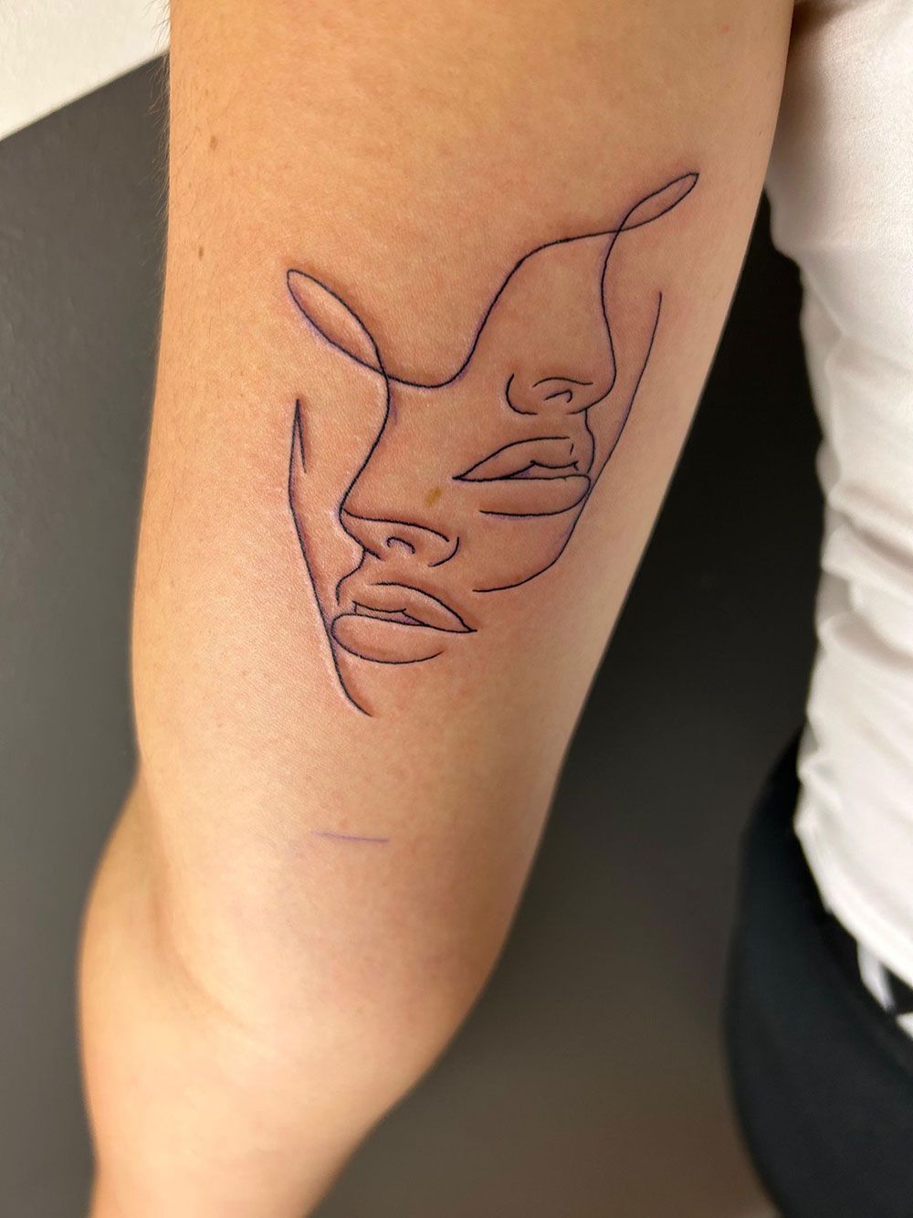 Eine Frau hat eine Tätowierung mit dem Gesicht einer Frau auf ihrem Arm.