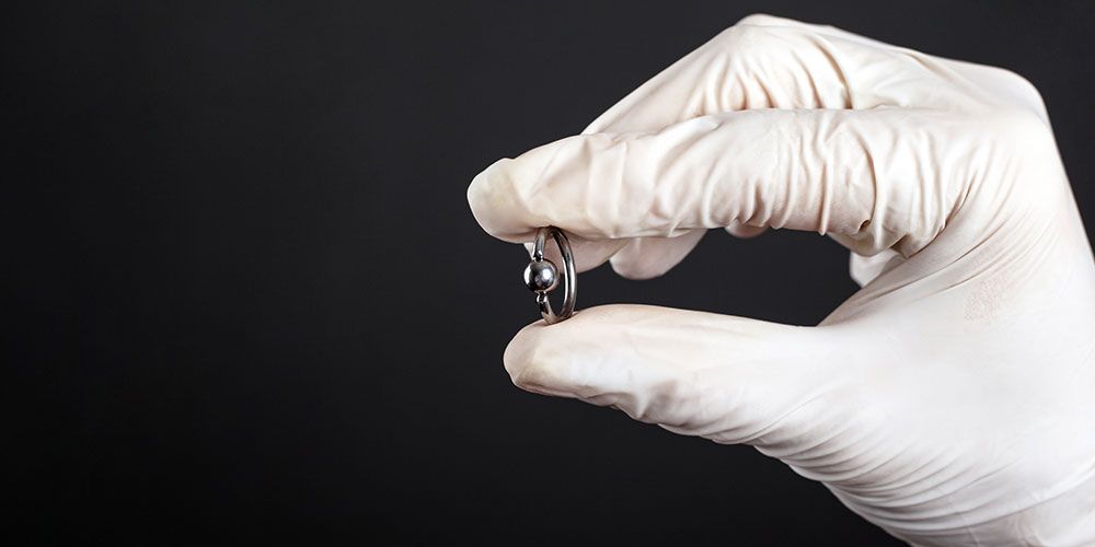 Eine Person mit einem weißen Handschuh hält einen kleinen Gegenstand in der Hand.