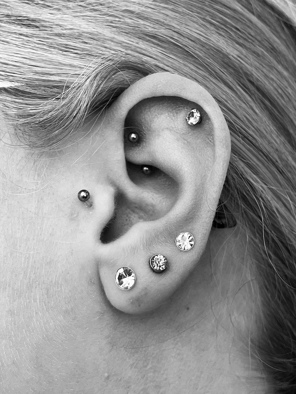 Eine Nahaufnahme des Ohrs einer Frau mit mehreren Piercings.