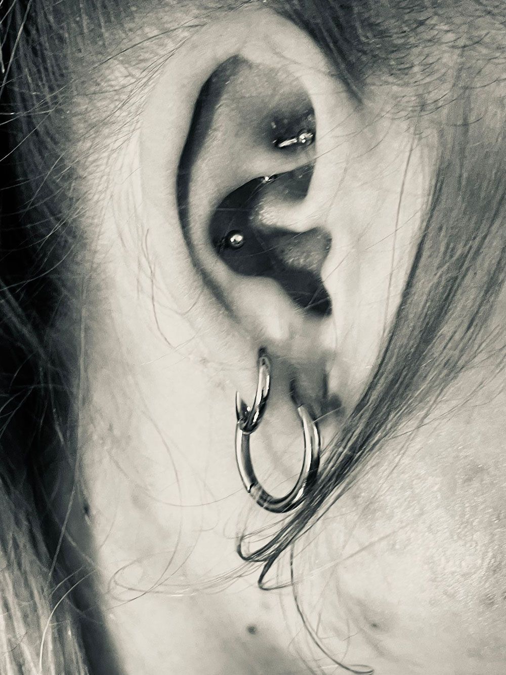 Eine Nahaufnahme des Ohrs einer Person mit mehreren Piercings.