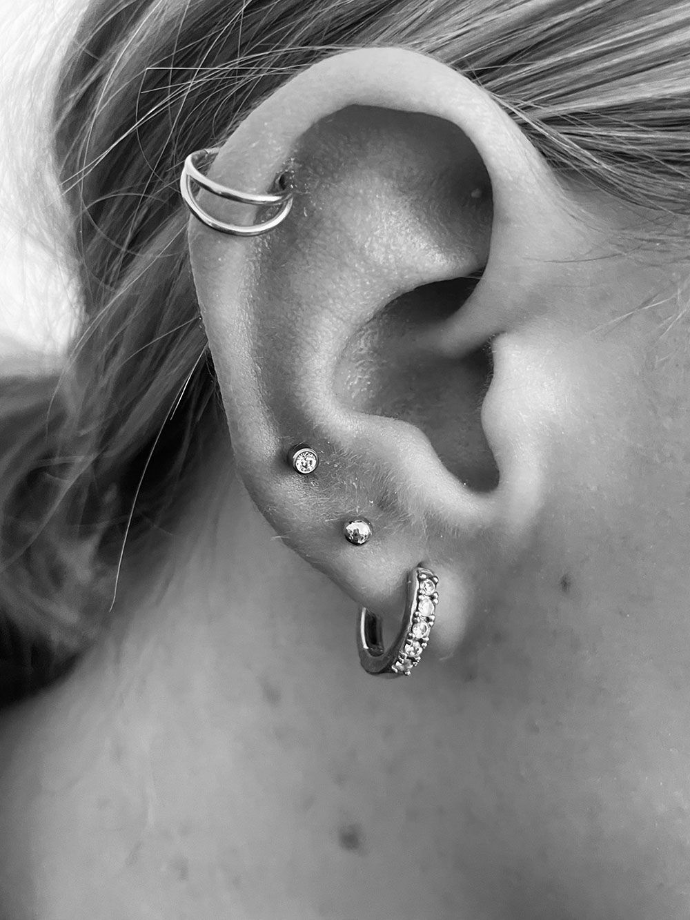 Eine Nahaufnahme des Ohrs einer Frau mit mehreren Piercings.