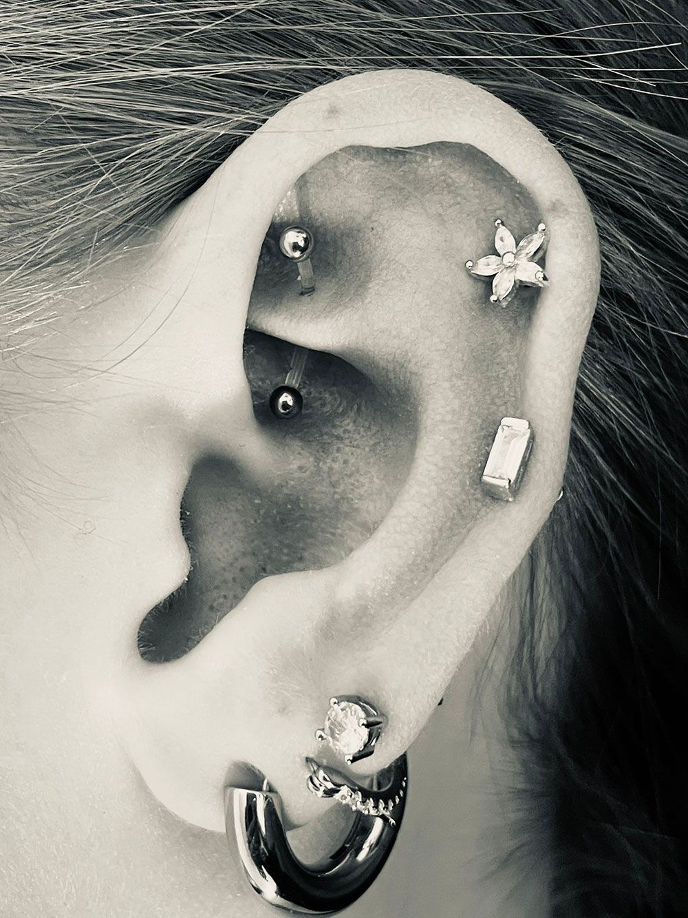 Eine Nahaufnahme vom Ohr einer Person mit vielen Piercings.