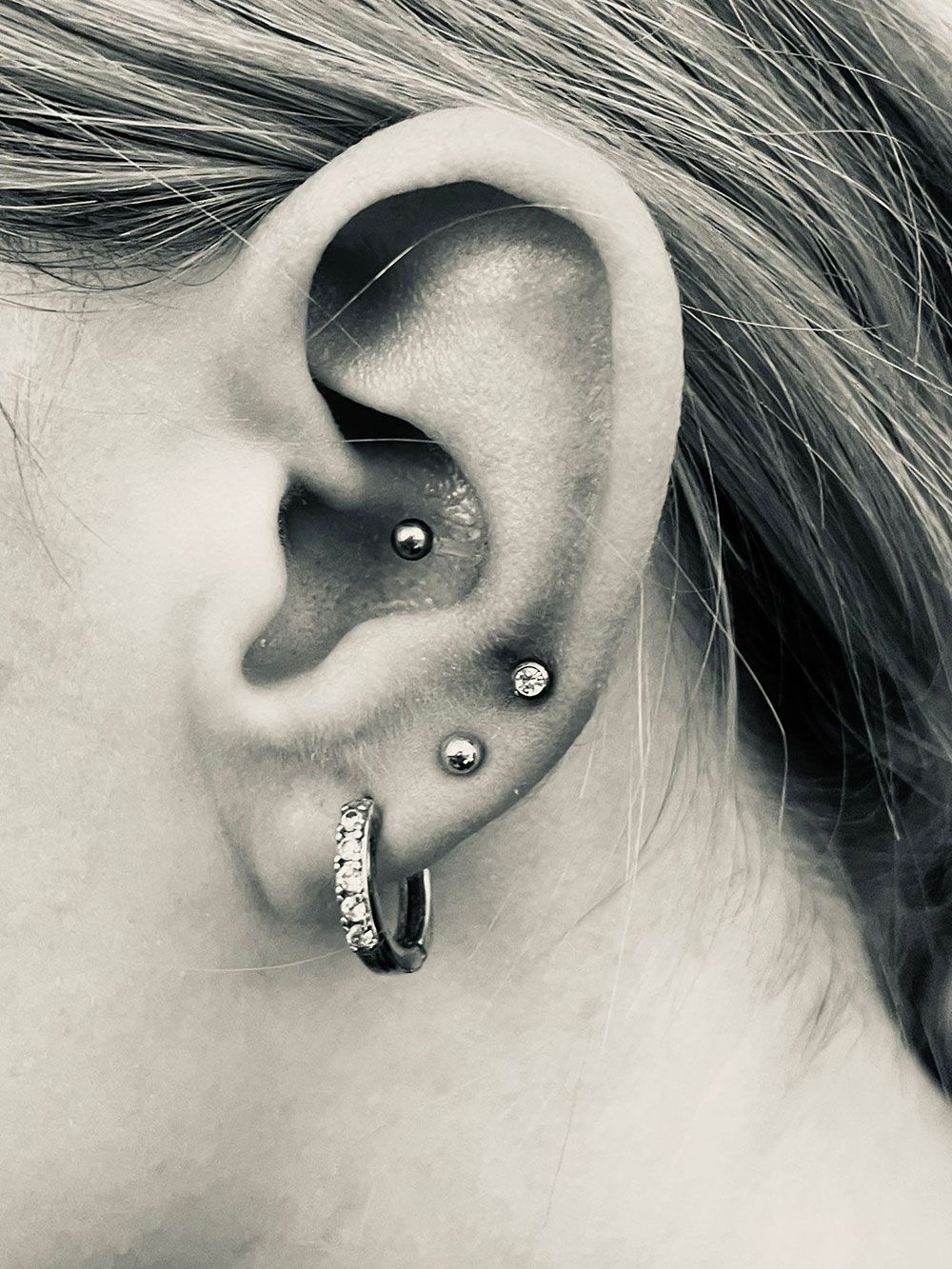 Eine Nahaufnahme des Ohrs einer Frau mit mehreren Piercings.