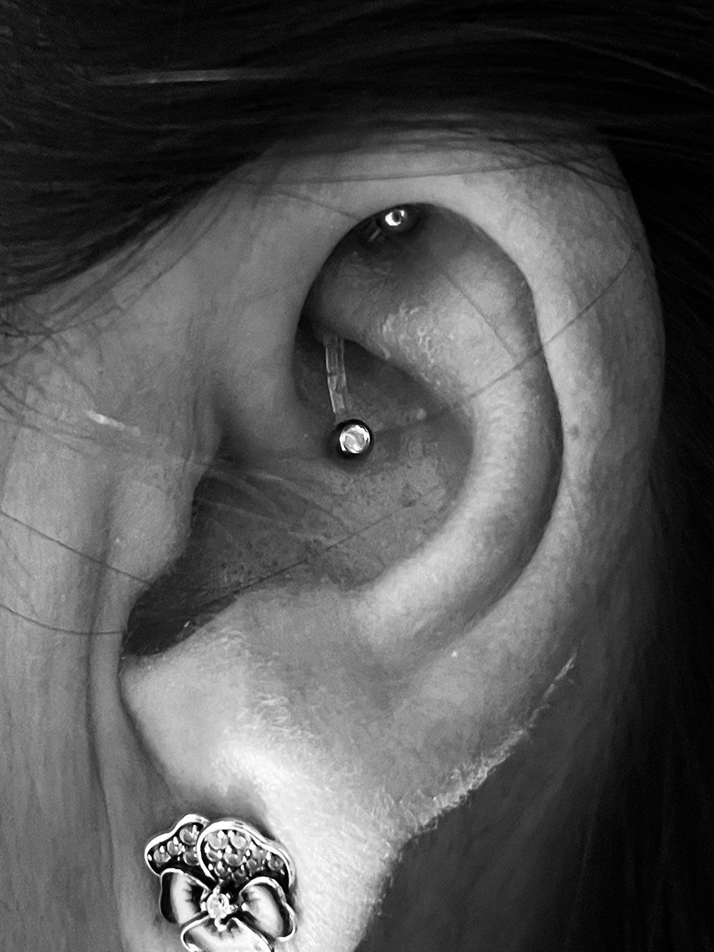 Eine Nahaufnahme des Ohrs einer Frau mit einem Piercing und Ohrringen.