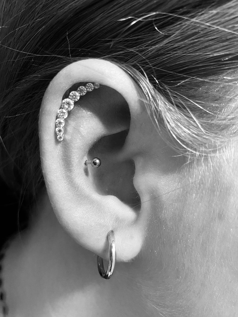 Ein Schwarzweißfoto eines Frauenohrs mit Ohrringen.