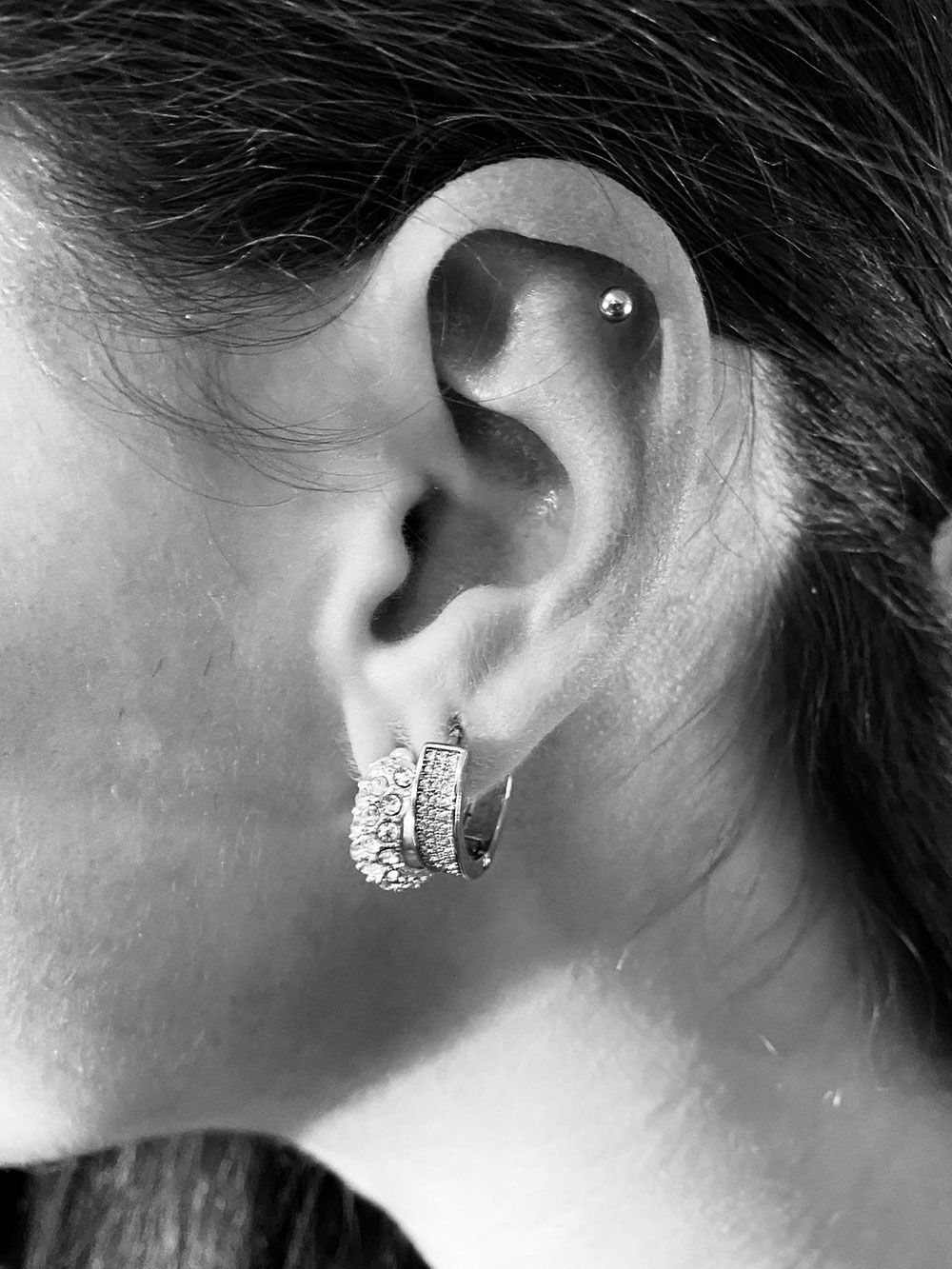 Ein Schwarzweißfoto eines Frauenohrs mit Ohrringen.
